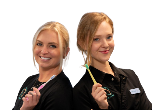 Two women wearing black shirts stand back to back, smiling and holding toothbrushes. One has a pink toothbrush, the other yellow—both with light hair and confident, friendly looks that suggest they’re dental professionals promoting teeth cleaning.
