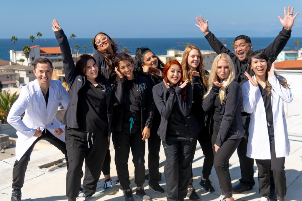 Dr. Gregory Shvartsman and Dr. Gloria Luong in white lab coats stand the whole team of South Redondo Dental Group